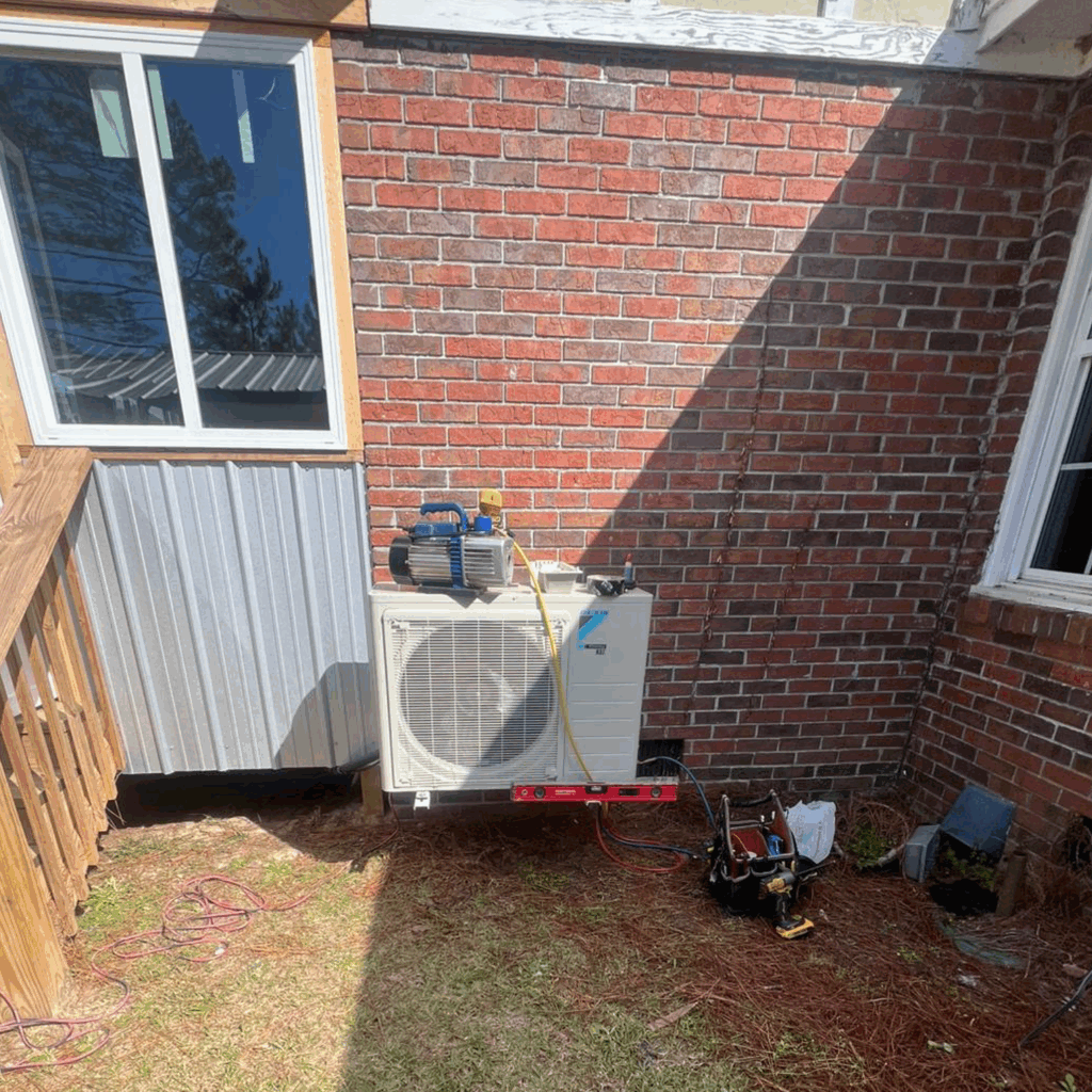 Air conditioning unit installed on a brick wall outside a house.