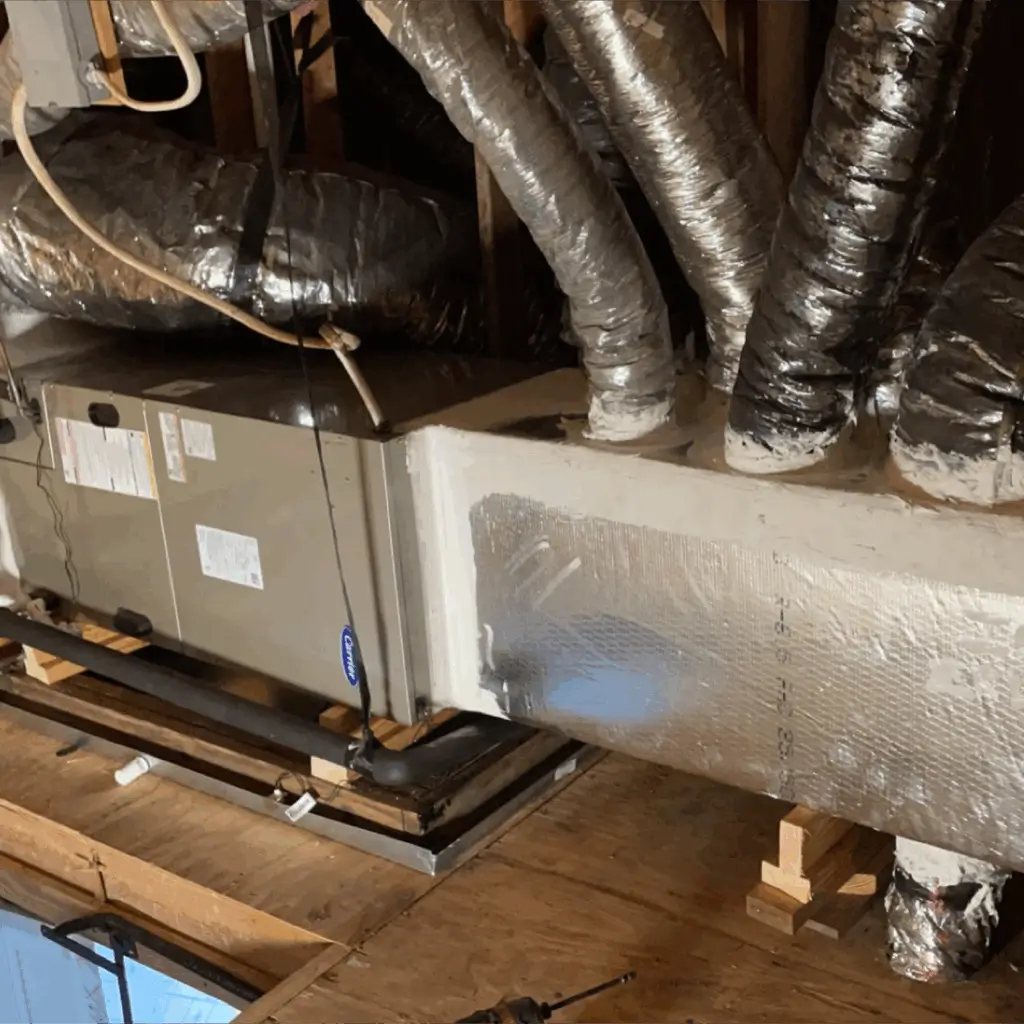 HVAC system with ductwork and insulated pipes in a ceiling space.