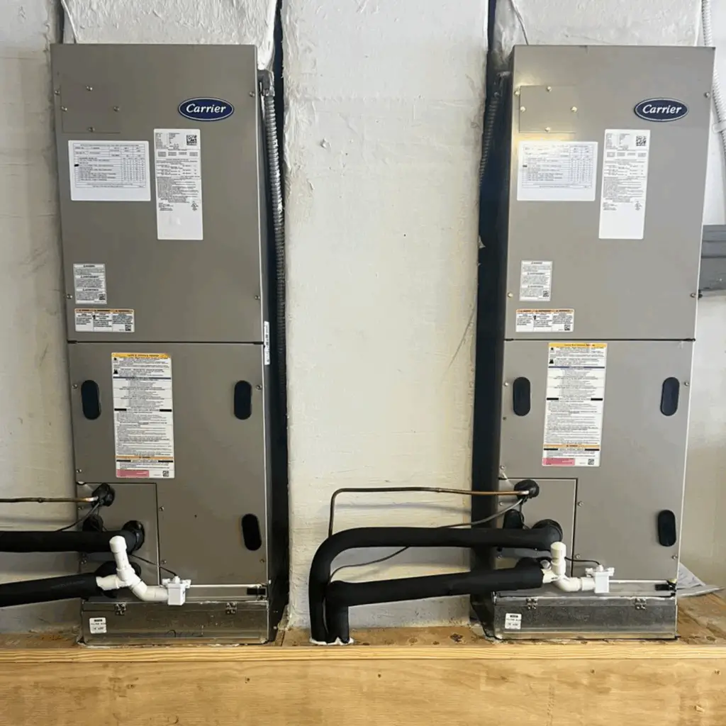 Two Carrier HVAC units installed side by side with piping connections.